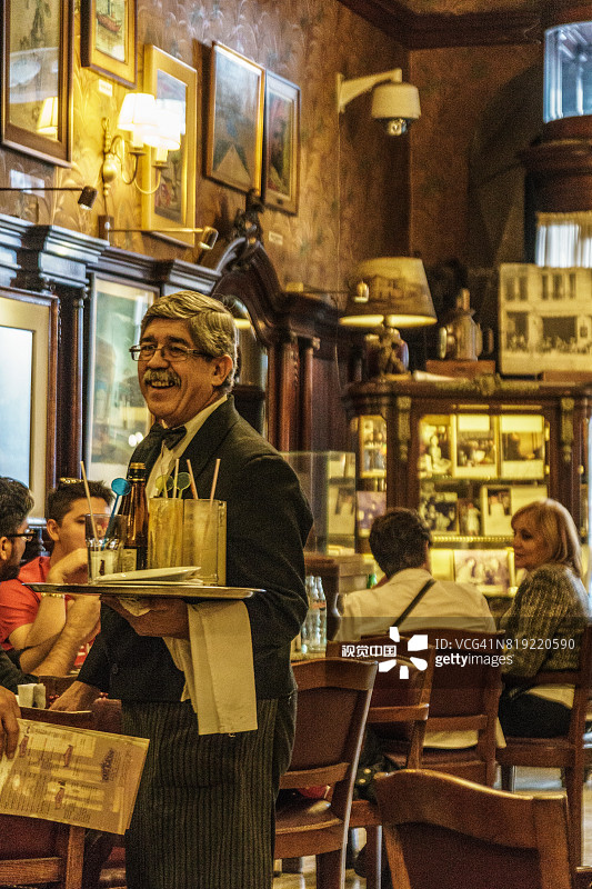 在阿根廷布宜诺斯艾利斯著名的托尔托尼咖啡馆，迷人的服务员端着饮料图片素材