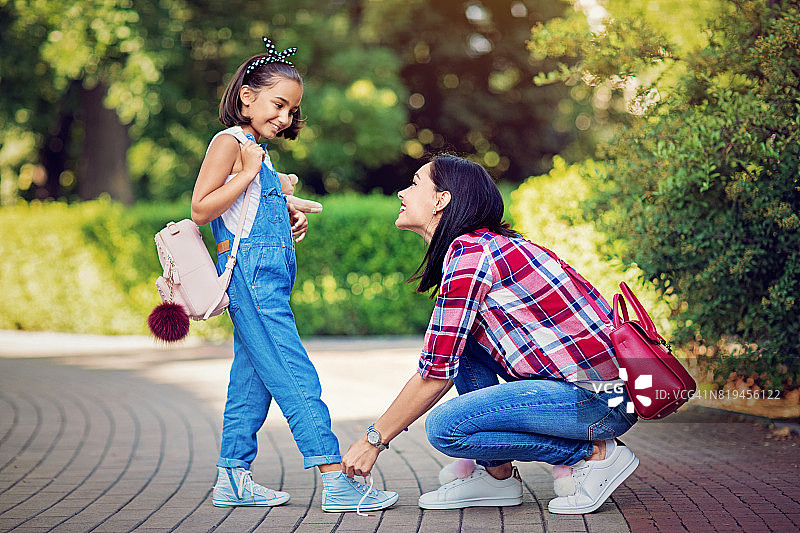母亲给心爱的女儿系鞋带图片素材