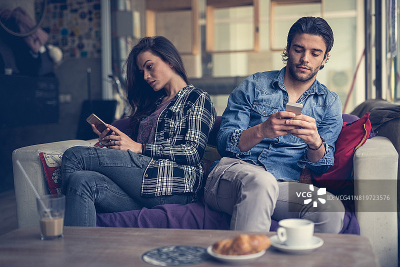 情侣在咖啡馆里各自玩手机图片素材