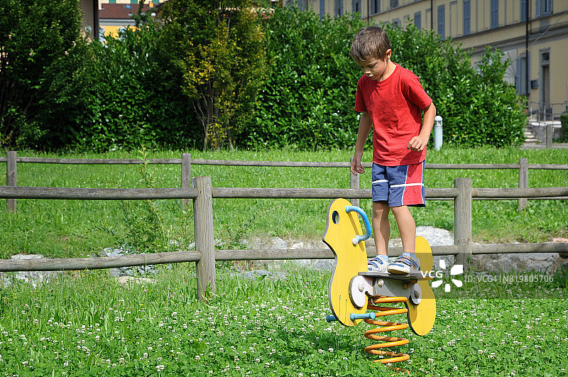 在操场上站在摇摆木马上的男孩图片素材