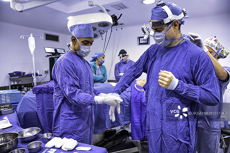 外科医生准备外科手术，助手帮忙戴手术手套图片素材