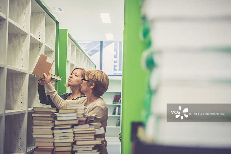 两位女图书管理员整理新图书馆的书籍图片素材