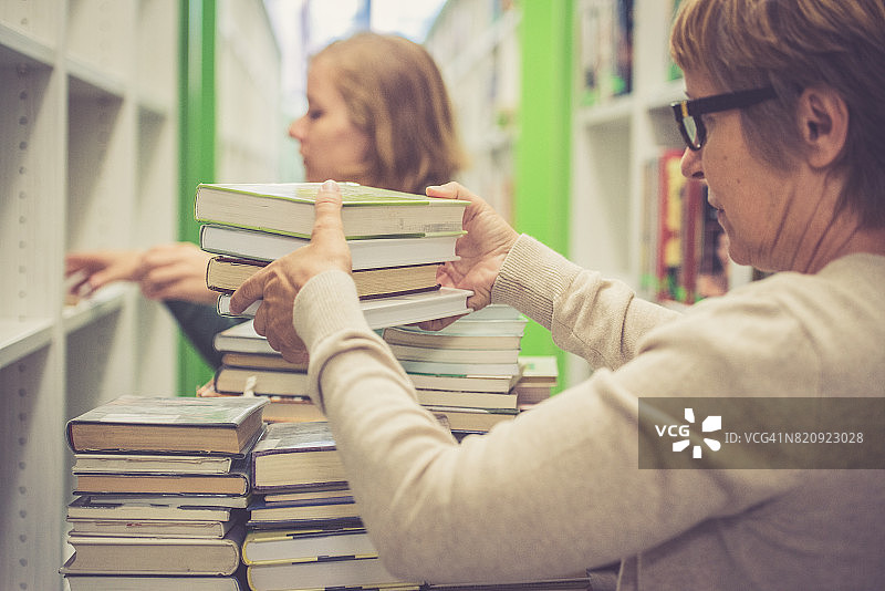 两位女图书管理员整理新图书馆的书籍图片素材