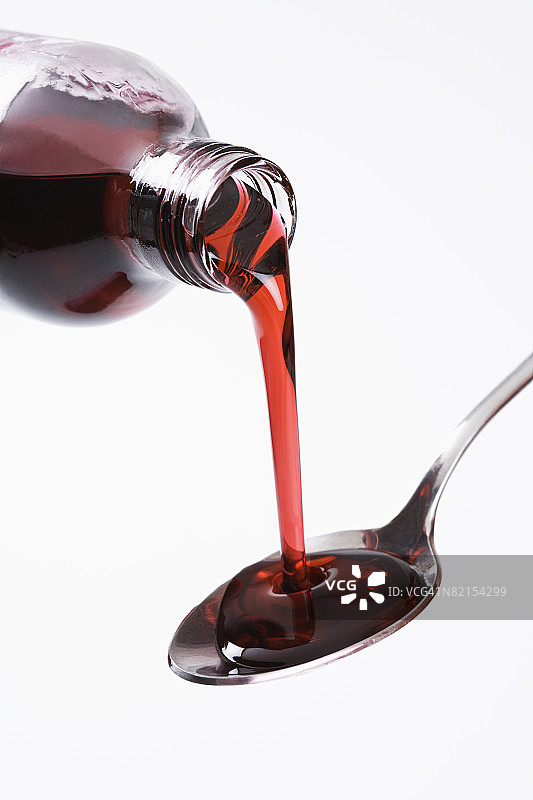 用勺子倾倒止咳糖浆的瓶子图片素材