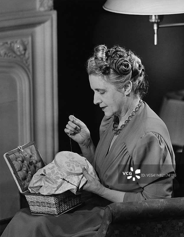 中年妇女坐在客厅里做针线活（黑白照片）图片素材