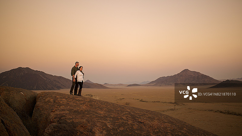 情侣在沙漠日落时拥抱图片素材
