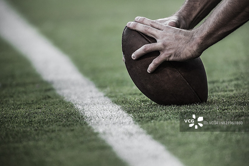 手放在美式橄榄球上图片素材