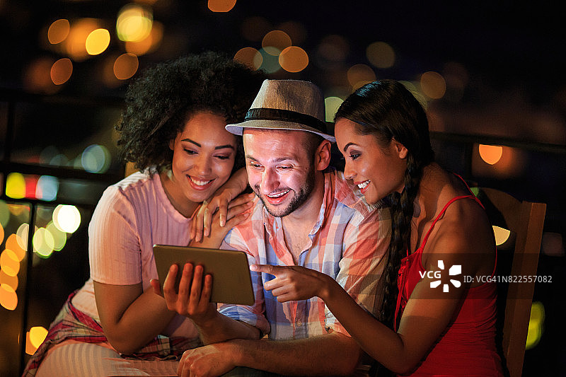 朋友们晚上一起玩平板电脑图片素材