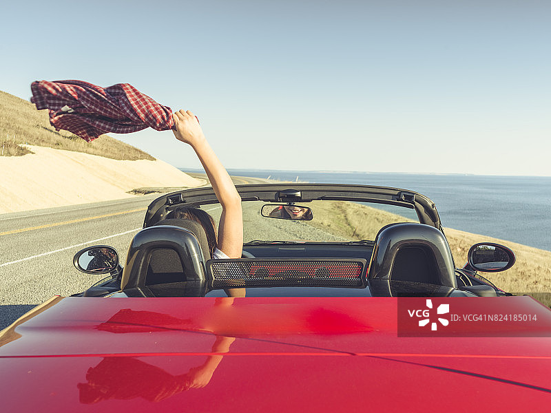 女人开车，手臂伸向空中感受微风图片素材