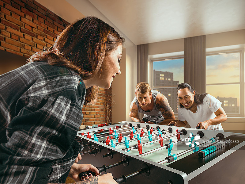 朋友们兴致勃勃地玩桌上足球游戏图片素材
