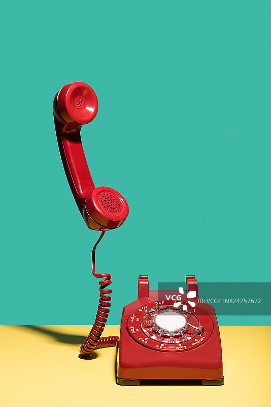 红色有线电话，听筒悬在空中图片素材