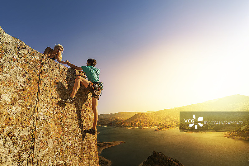 团队合作：夫妇互相帮助攀登图片素材