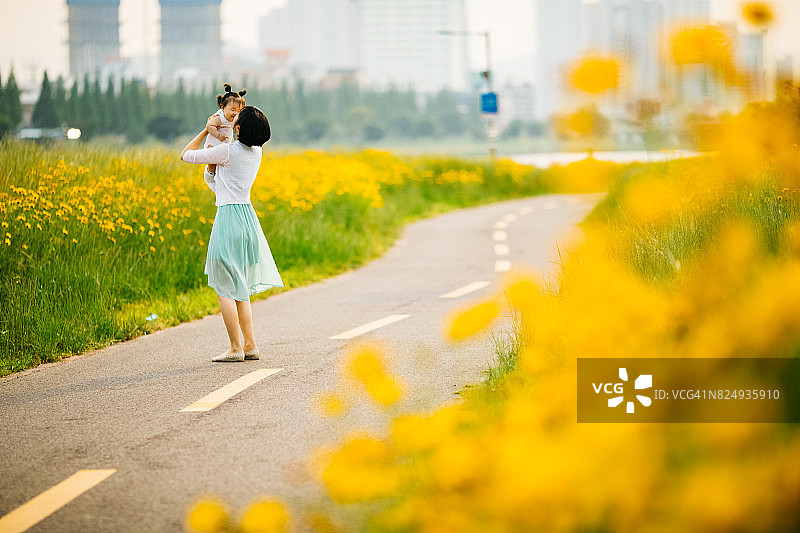 母亲在黄色花丛中亲吻女婴图片素材