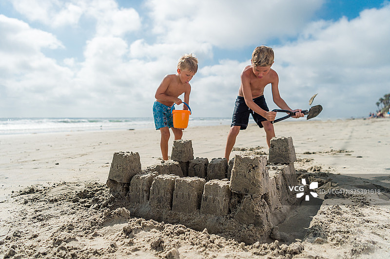 兄弟在海滩上建造沙堡图片素材