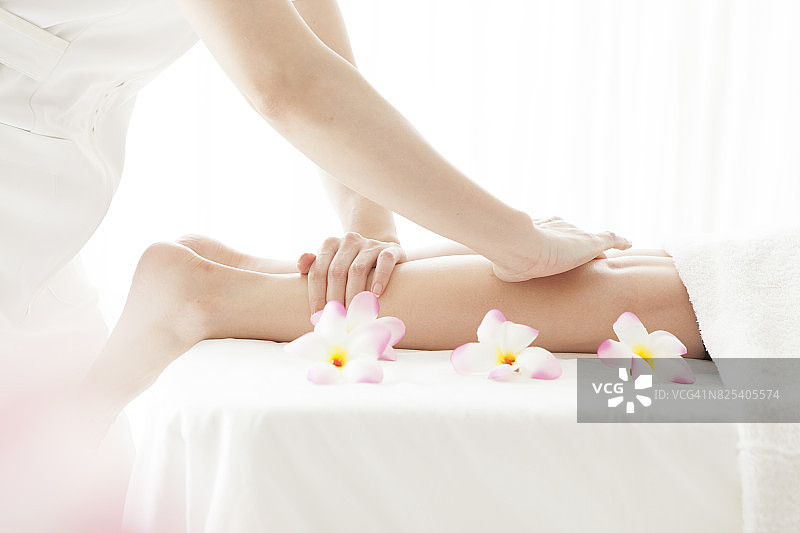 美容师为年轻漂亮的女士进行腿部按摩图片素材