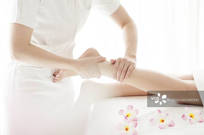 美容师为年轻漂亮的女士进行腿部按摩图片素材