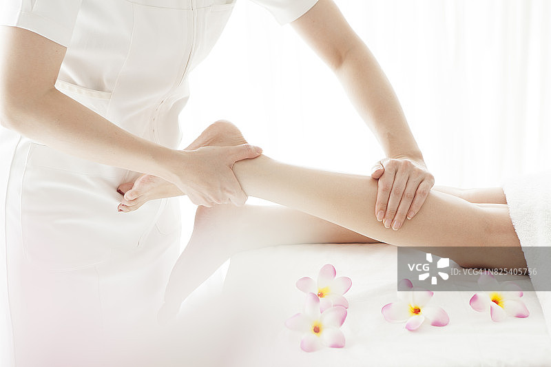 美容师为年轻漂亮的女士进行腿部按摩图片素材