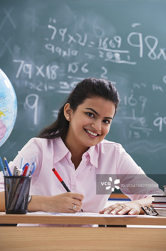 办公桌前的老师对着镜头微笑（竖版）图片素材