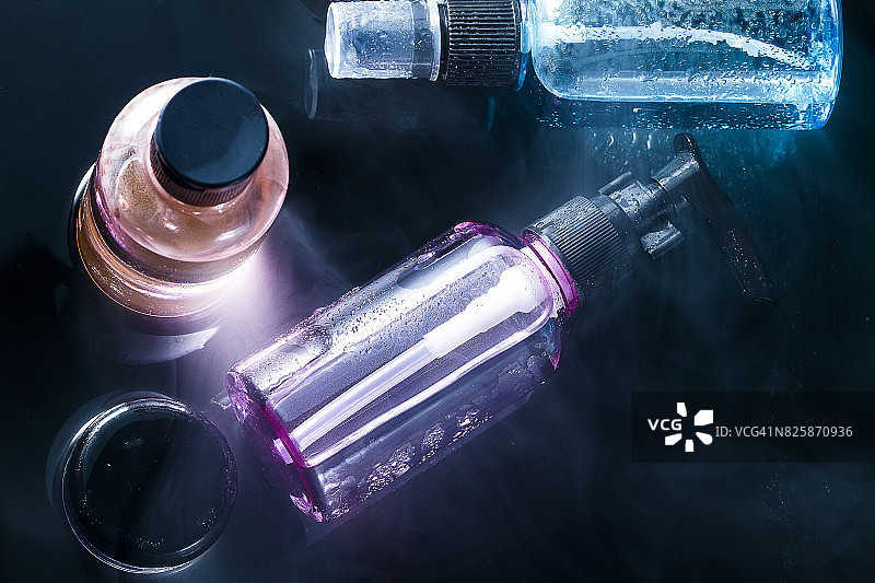 潮湿阴暗背景上的彩色逼真化妆品瓶子图片素材