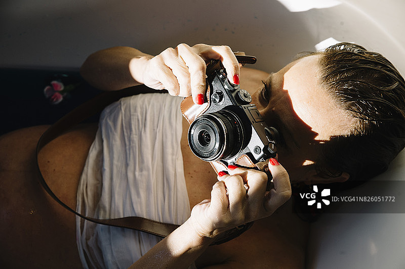 在浴缸里拿着照相机的女人图片素材