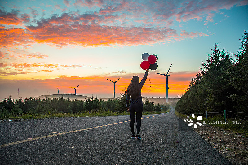 年轻女子在日落时分放气球图片素材