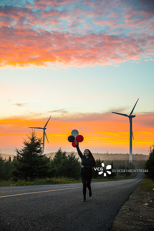 年轻女子在日落时分放气球图片素材