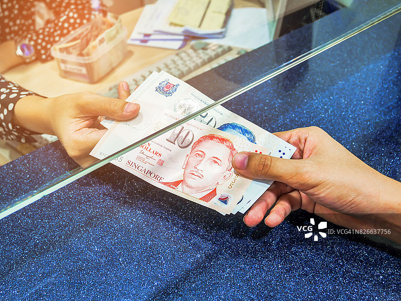 女人在现金部门窗口用手拿钱，货币兑换概念，新加坡元，银行柜台现金，给予和接受现金，发薪日支付收银员图片素材