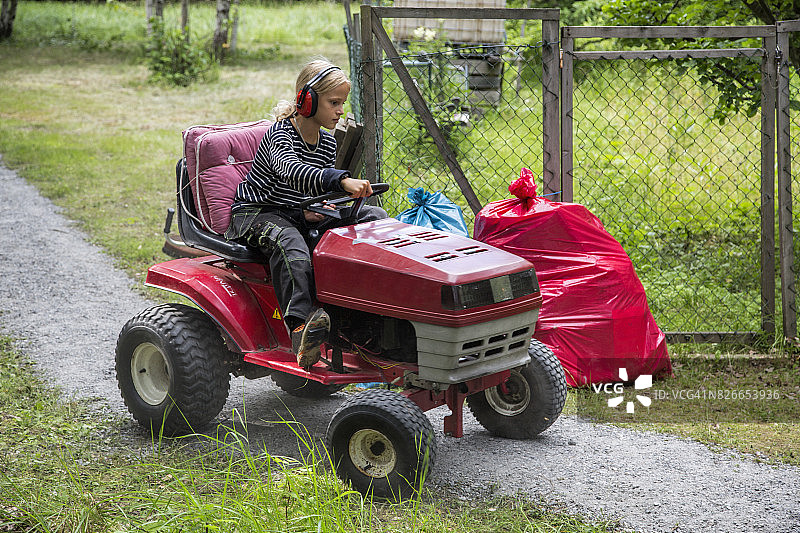 戴着护耳器的男孩小心驾驶迷你拖拉机图片素材