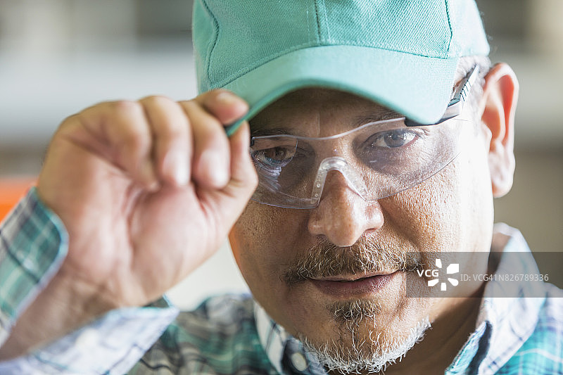 戴安全眼镜、帽子和格子衬衫的西班牙裔工人图片素材