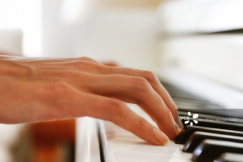 右手在白色钢琴上弹奏琴键的特写图片素材