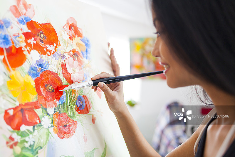 微笑的女艺术家在工作室里绘画图片素材