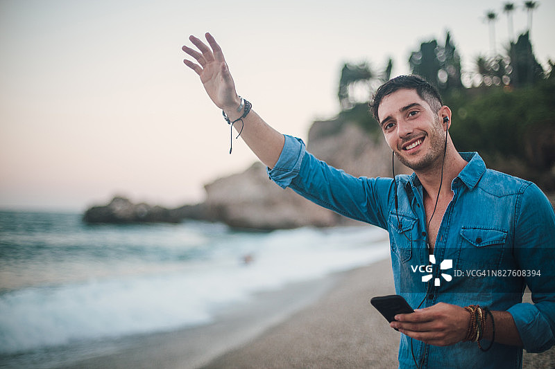 在海滩上挥手的年轻男人图片素材