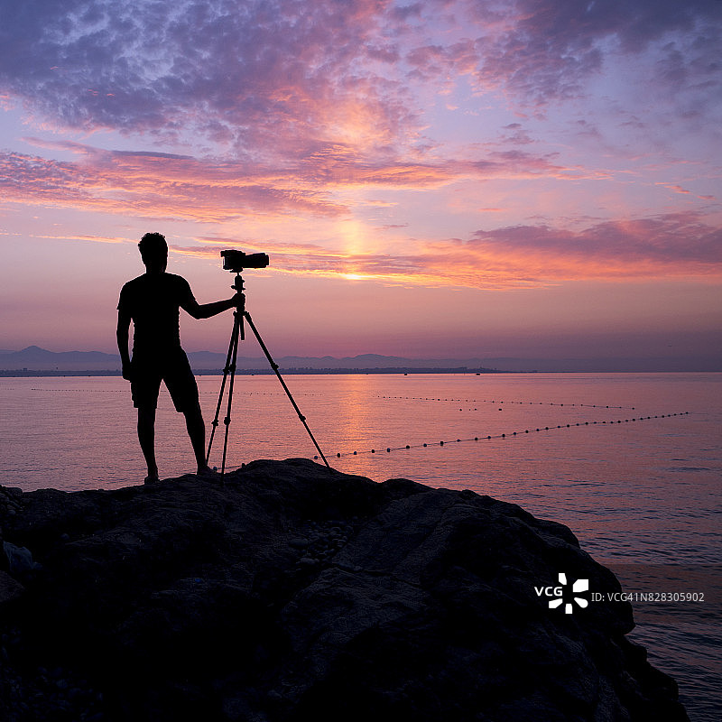 摄影师在黎明时分拍摄日出图片素材