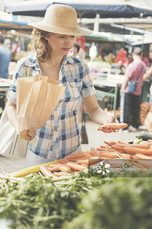 女人在农贸市场挑选胡萝卜图片素材
