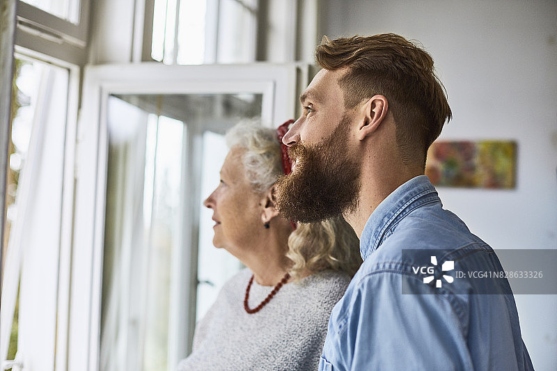 母亲和成年儿子在看窗外图片素材