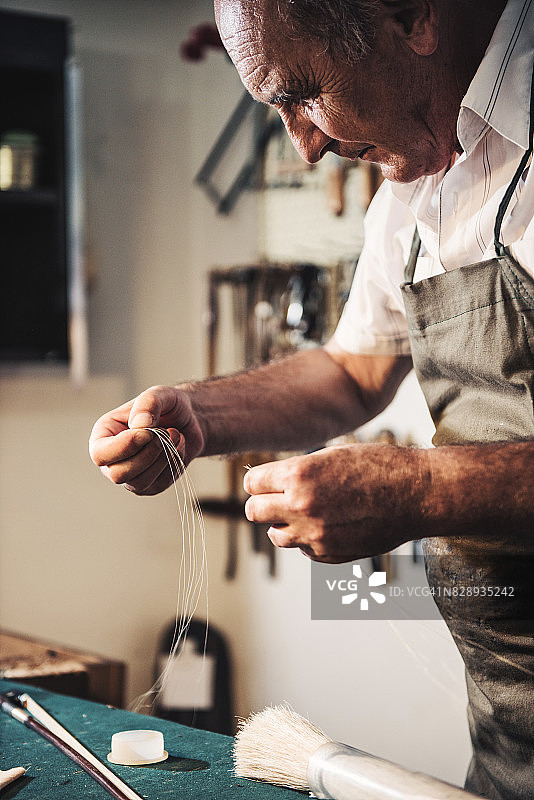 在弦乐器店工作的年长修理工图片素材