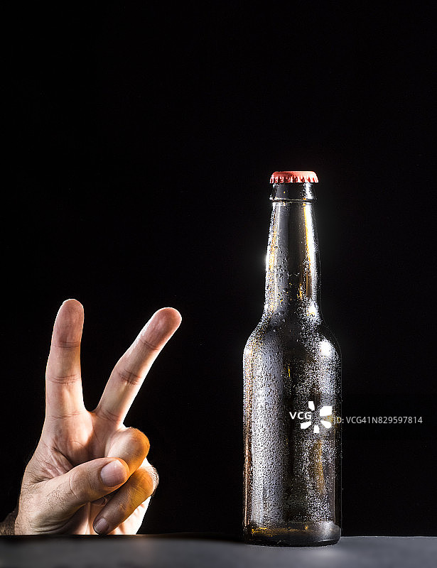 水滴玻璃瓶装啤酒和手势图片素材