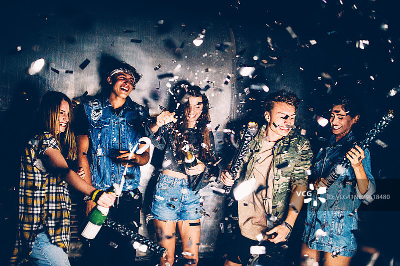 年轻的朋友们在派对上庆祝，香槟和彩纸飞舞图片素材