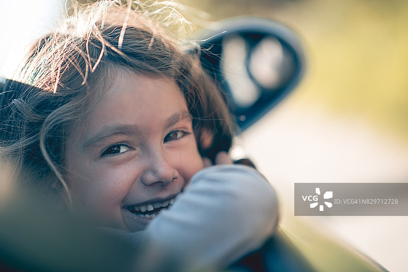 可爱微笑小女孩在车窗外摆姿势图片素材
