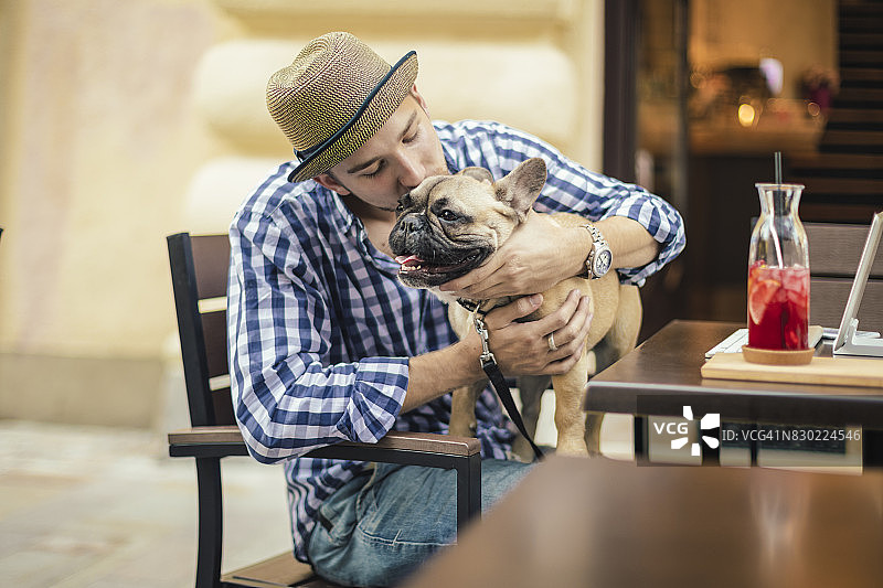 在城市里与法国斗牛犬在一起的年轻男人图片素材