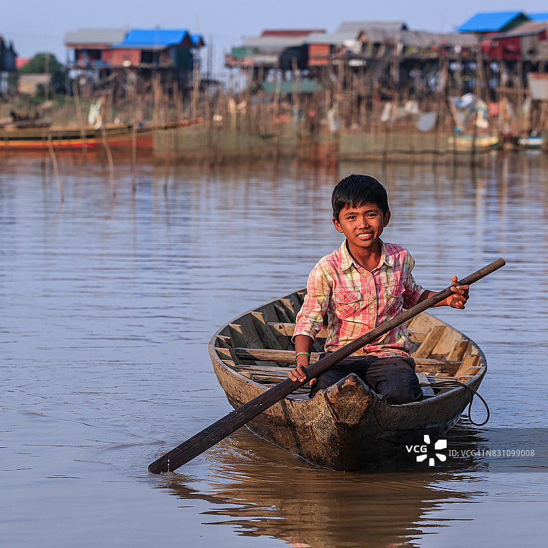 在柬埔寨洞里萨湖上划船的柬埔寨男孩图片素材