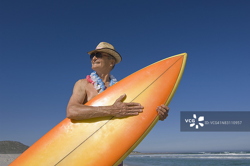 在海滩上拿着冲浪板的赤膊男人图片素材