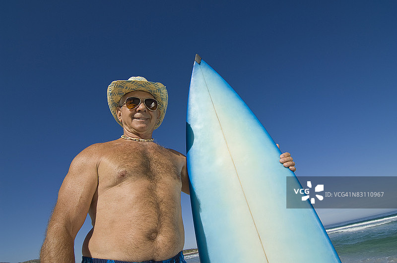 在海滩上拿着冲浪板的赤膊男人图片素材