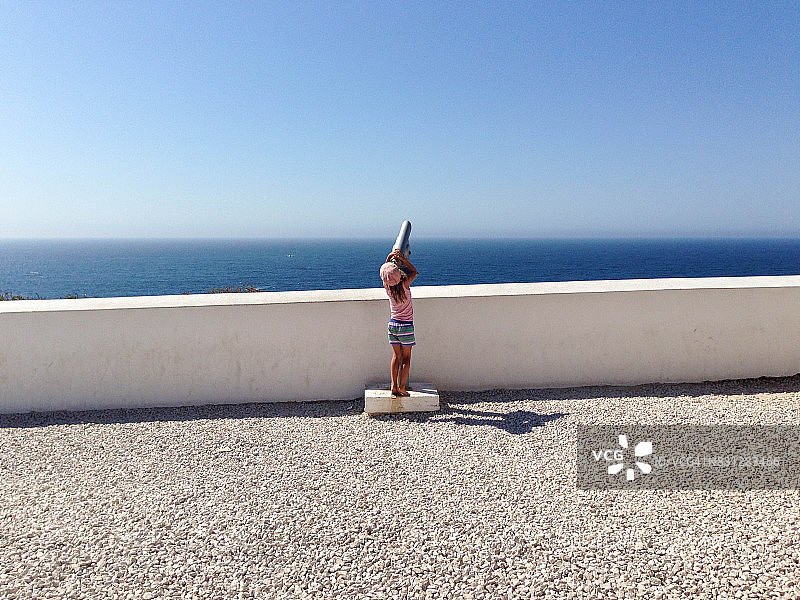 孩子试图通过投币式望远镜看向天空图片素材