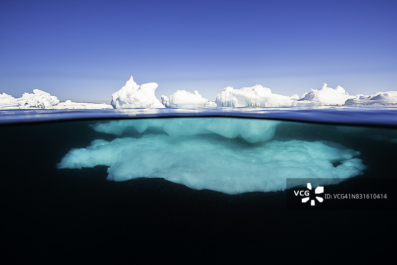 阳光明媚的日子里，加拿大巴芬岛北部阿德米勒湾冰缘的冰层水线上下景观图片素材