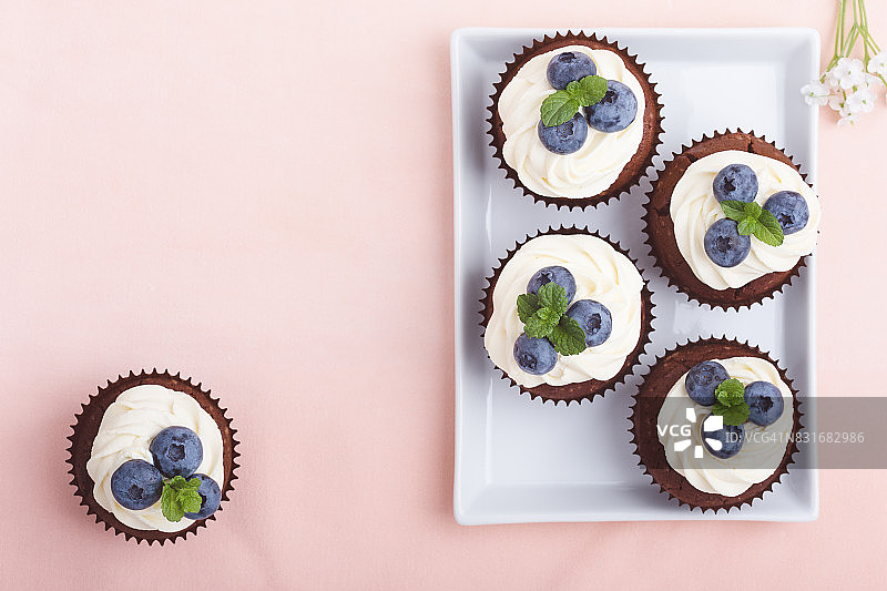 节日：粉红色桌子上的奶油奶酪巧克力纸杯蛋糕图片素材