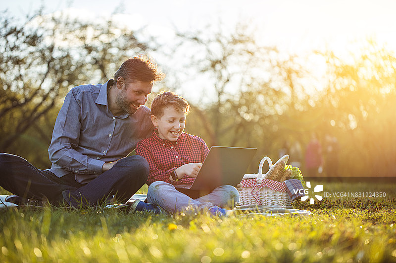 父子在野餐时使用平板电脑欢笑图片素材