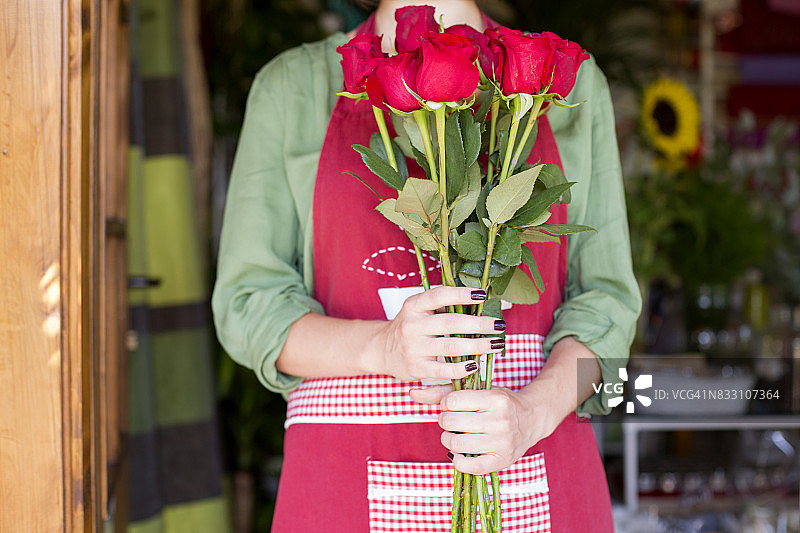 手持红玫瑰的年轻花艺师图片素材