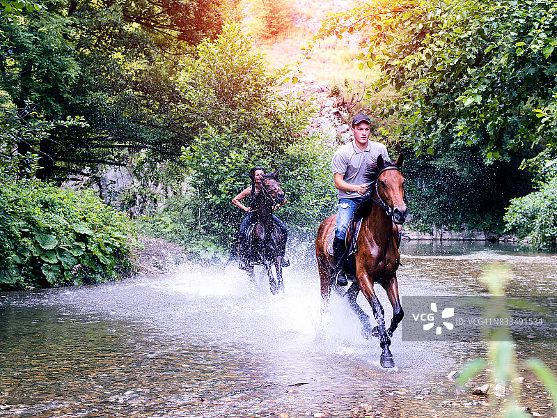 情侣在溪流中骑马图片素材