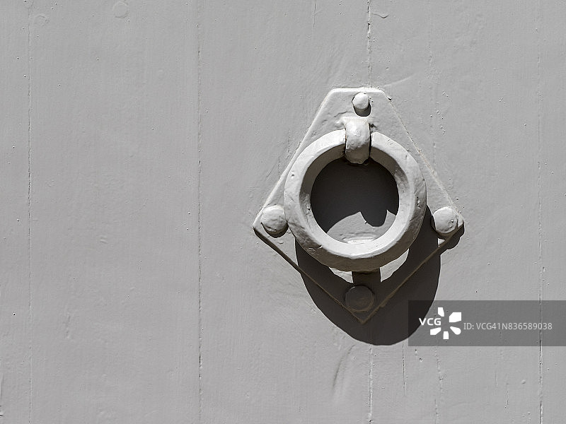 西班牙瓦伦西亚的阳光照耀下的光滑木质灰色门和金属圆形门环图片素材